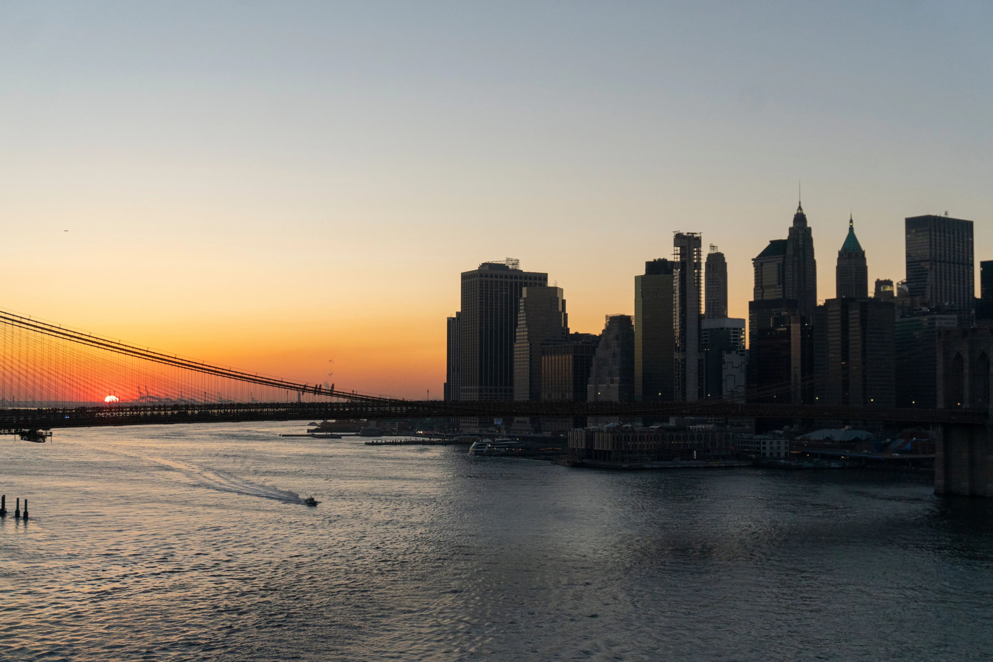 Photo city skyline beside bridge at sunset over river