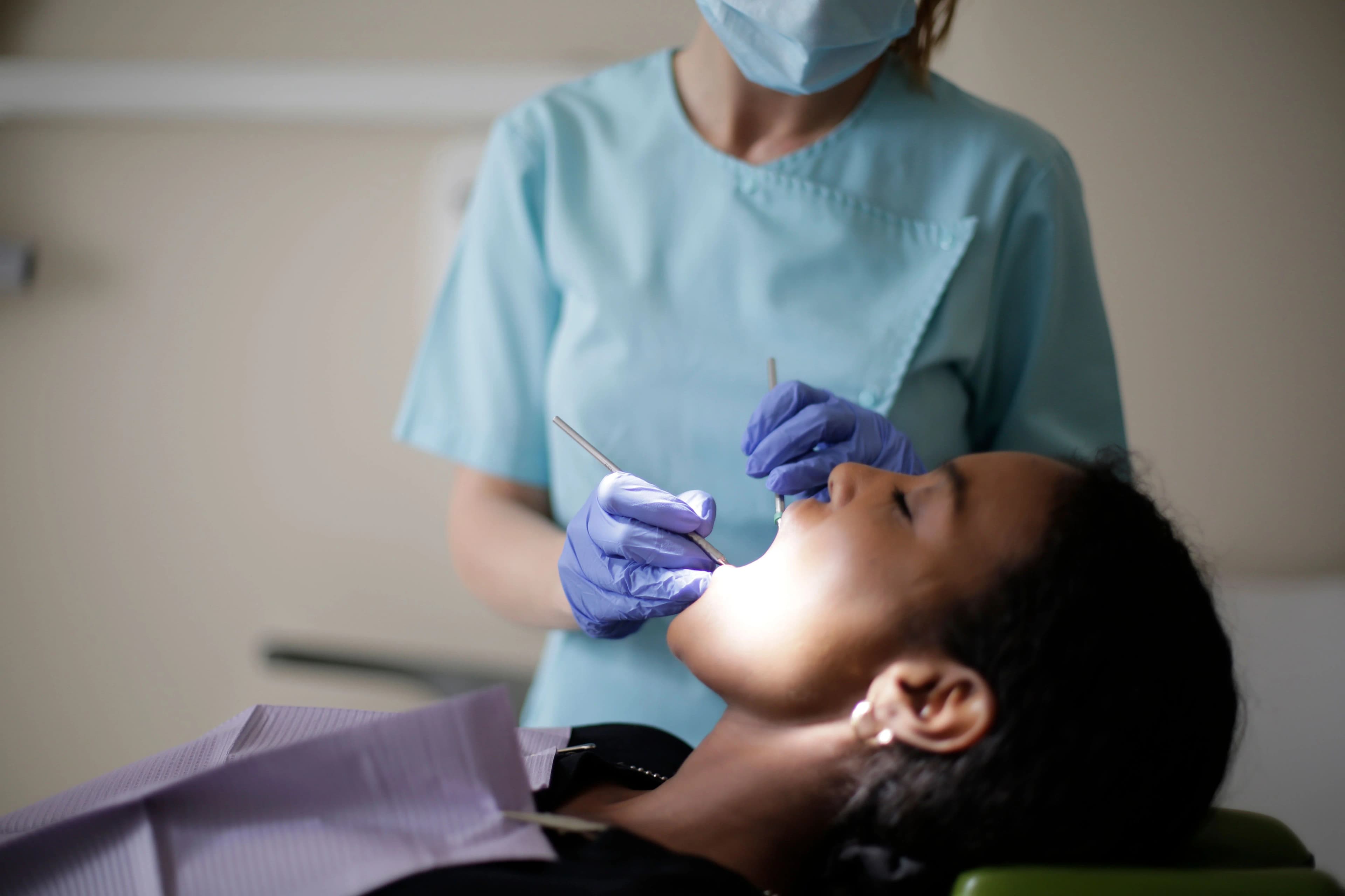 Photo dental professional examining patient’s mouth with dental instruments