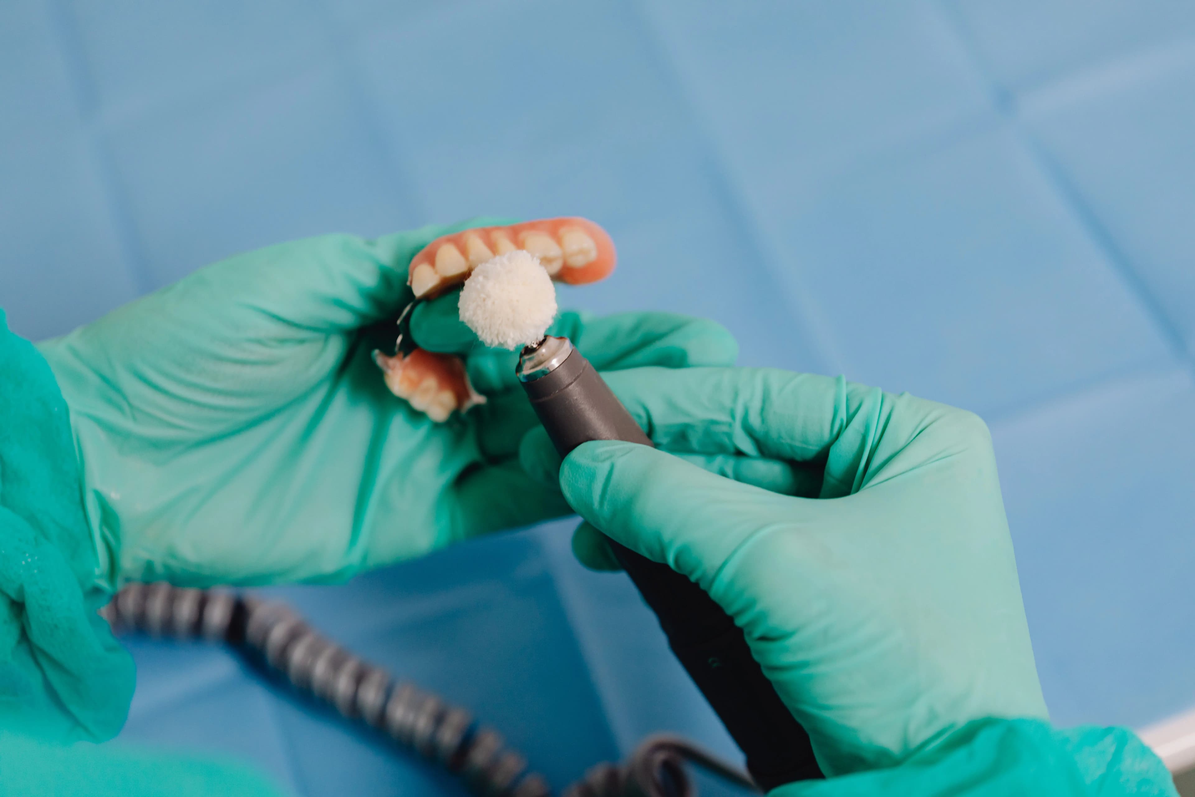 A dental professional polishing a denture at Smile4Me Dental Care