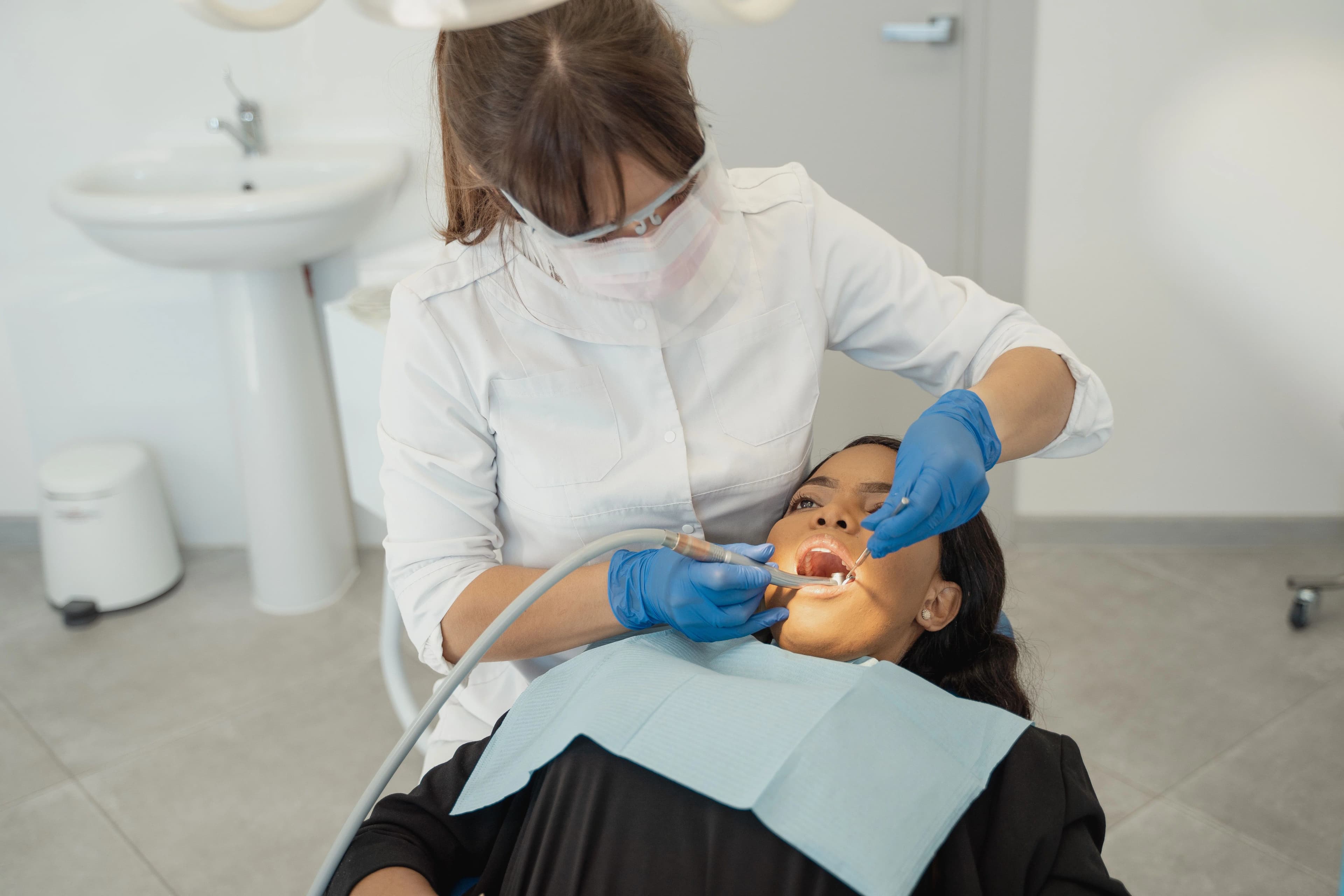 Photo dentist performing preventative dental care in Astoria on patient in dental chair