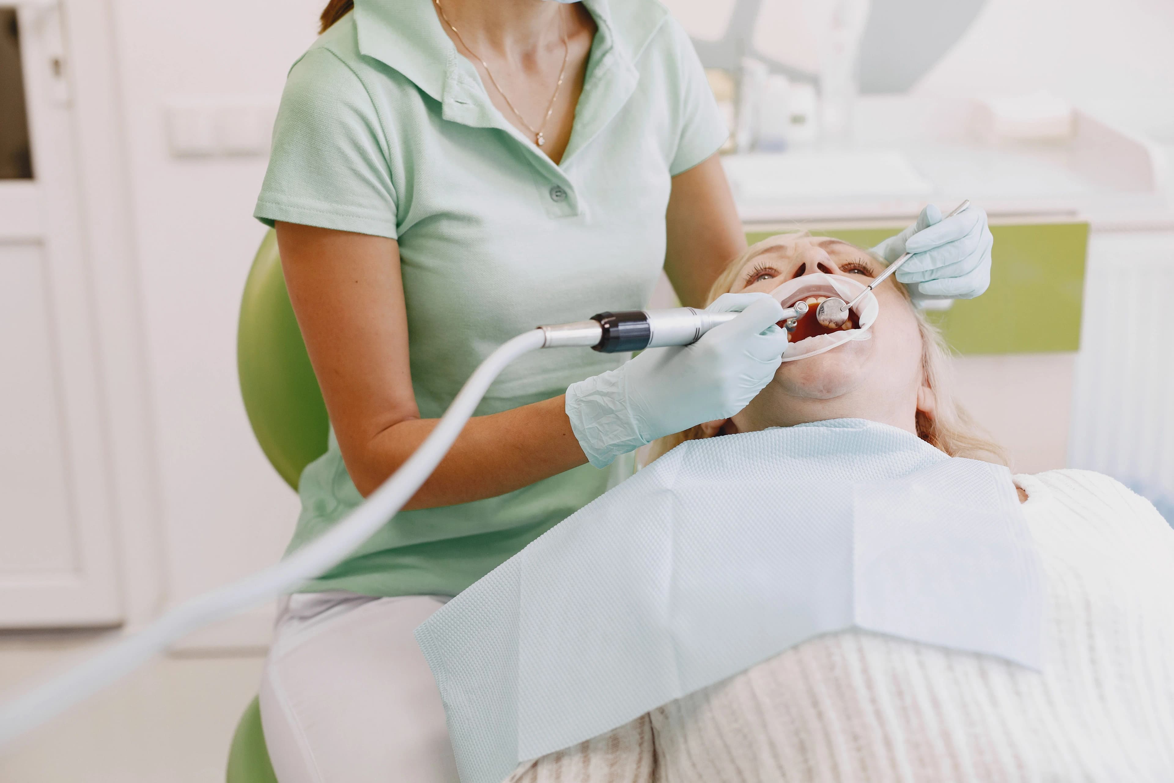 Photo dentist providing preventative dental care in Astoria while treating reclining patient