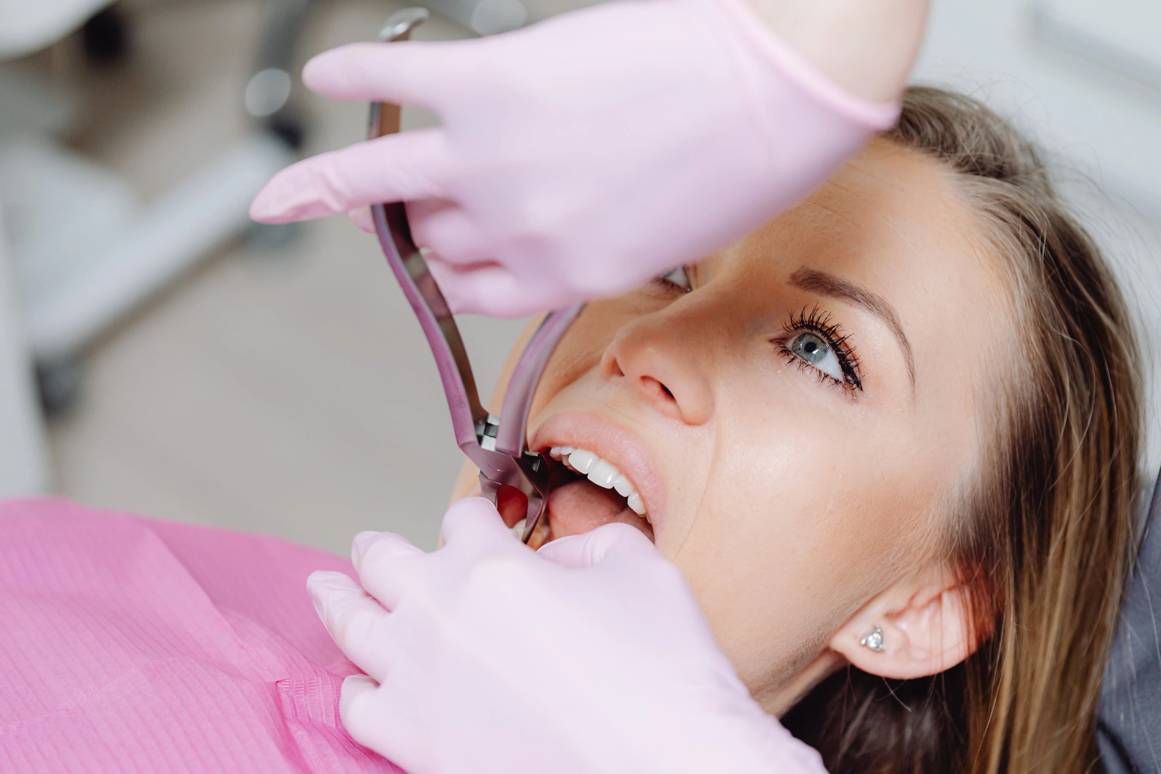 Photo patient receiving oral exams in astoria with dental extraction forceps during examination