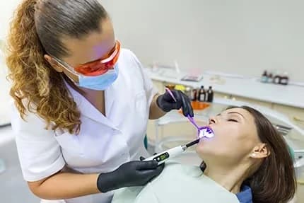 Dental professional performing a teeth whitening procedure on a patient in a dental chair