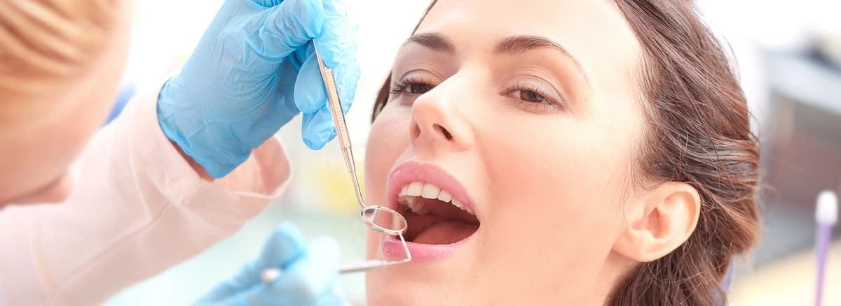 photo-patient-receiving-oral-exam-from-emergency-dentist-astoria-with-dental-mirror-and-tools