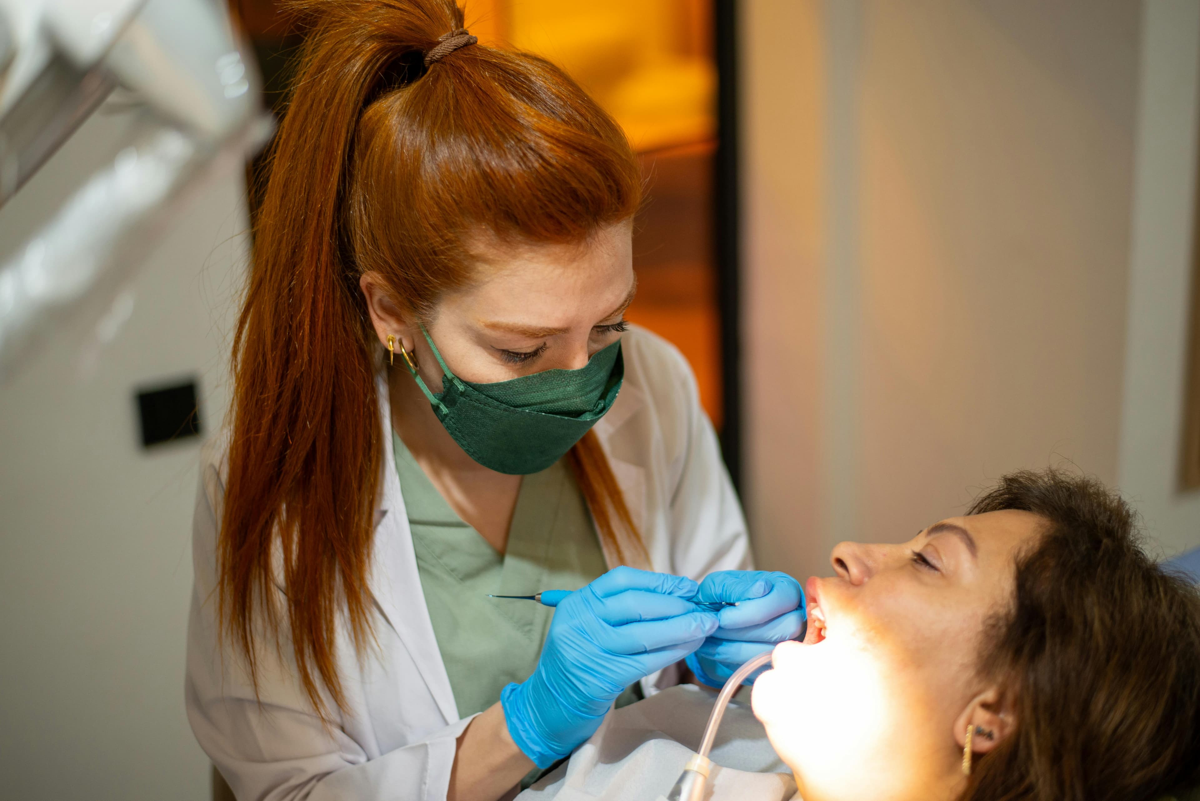 Photo Dentist Wearing Mask And Blue Gloves Treating Patient In Dental Chair As Patient Asks Is Losing A Filling A Dental Emergency