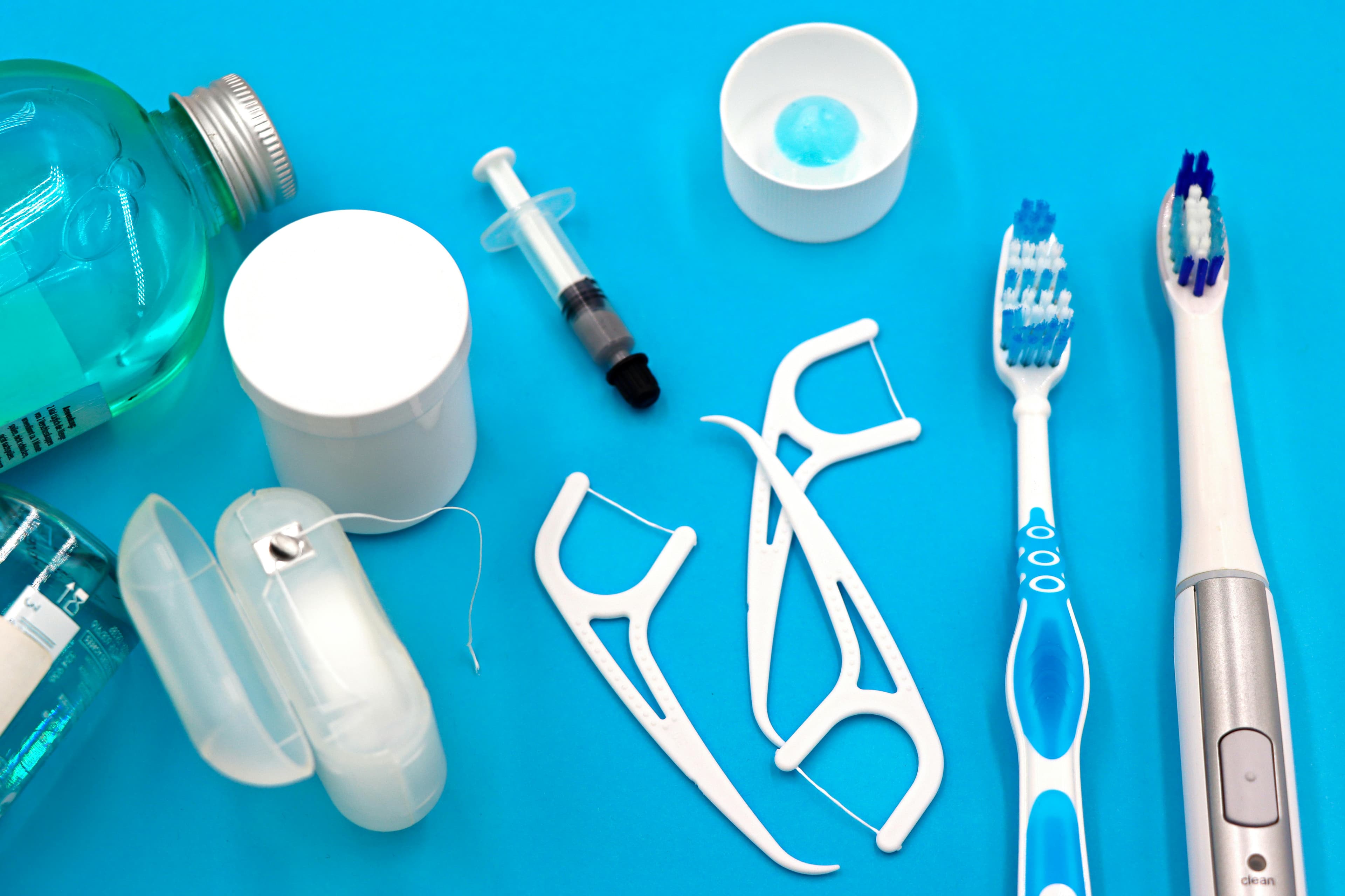 Photo Dental Emergency Preparedness Items Including Toothbrushes Electric Toothbrush Floss Picks Mouthwash Container Syringe And Small Bowl On Blue Background