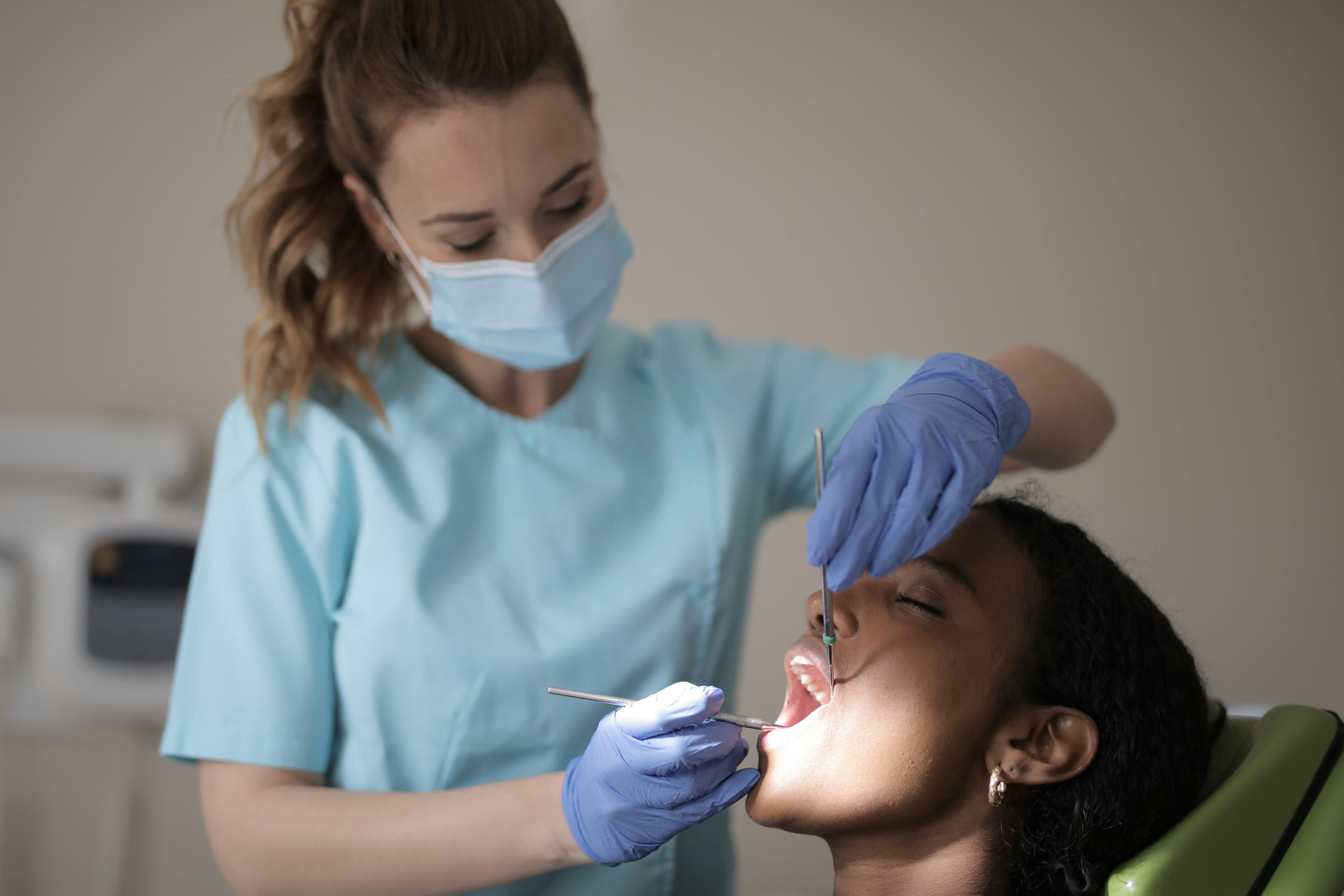Photo Dentist Wearing Mask And Gloves Examining Patient Teeth With Dental Tools In Chair Checking For Dental Emergency Signs