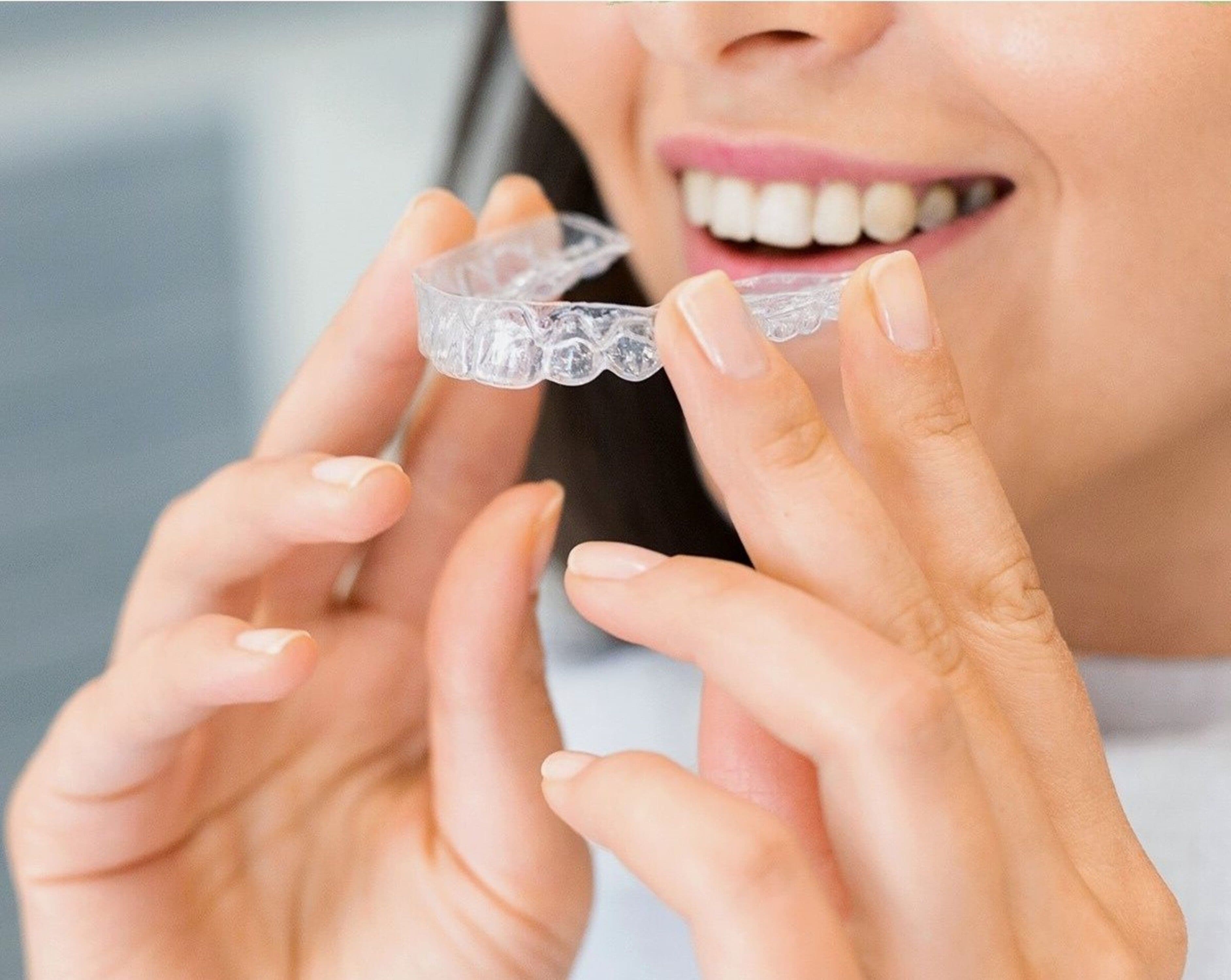 Photo Woman Holding Clear Aligner Showing How Often Are Invisalign Trays Changed