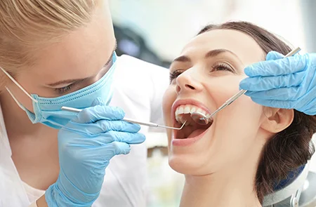 Dentist examining female patient with dental tools checking for oral health issues and signs your wisdom teeth are coming in during appointment.