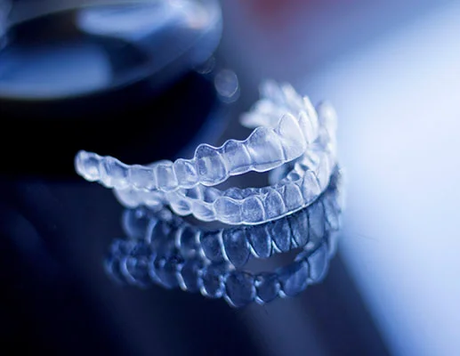 How long does Invisalign take - Pair of clear Invisalign aligners on reflective surface.
    