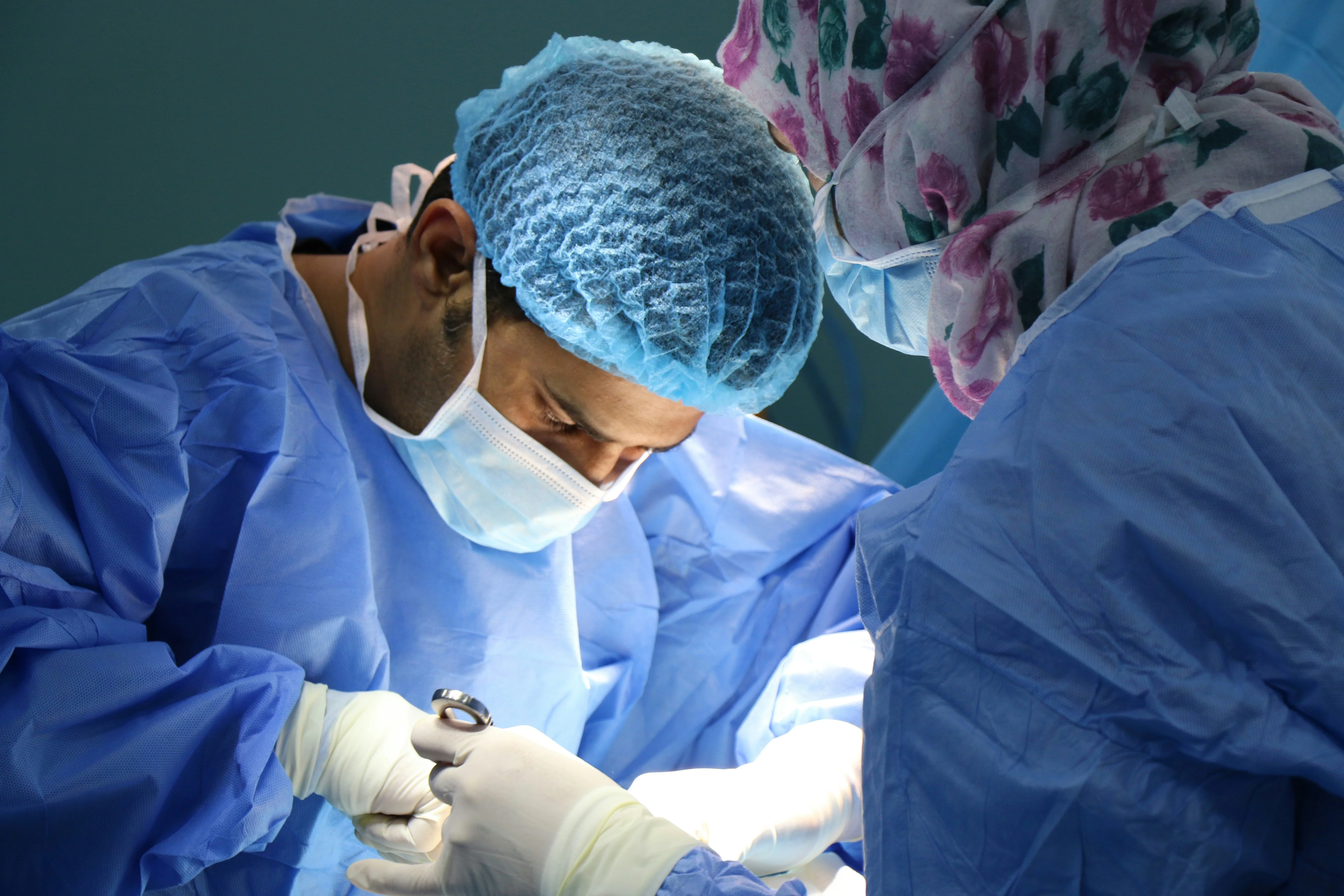 Two surgeons in blue surgical gowns performing procedure demonstrating critical scenarios of what qualifies as a dental emergency in hospital setting.