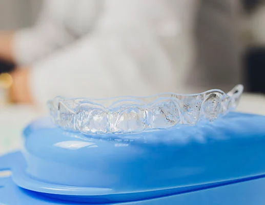 What are Invisalign aligners made of? - Clear Invisalign aligner resting on blue case with blurred background.